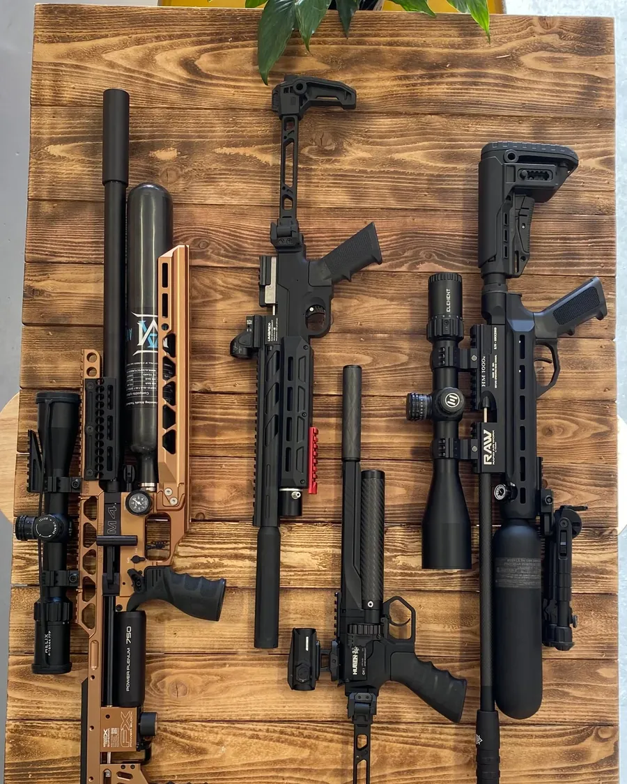 A rack of PCP air rifles and gear laid out on a wooden board